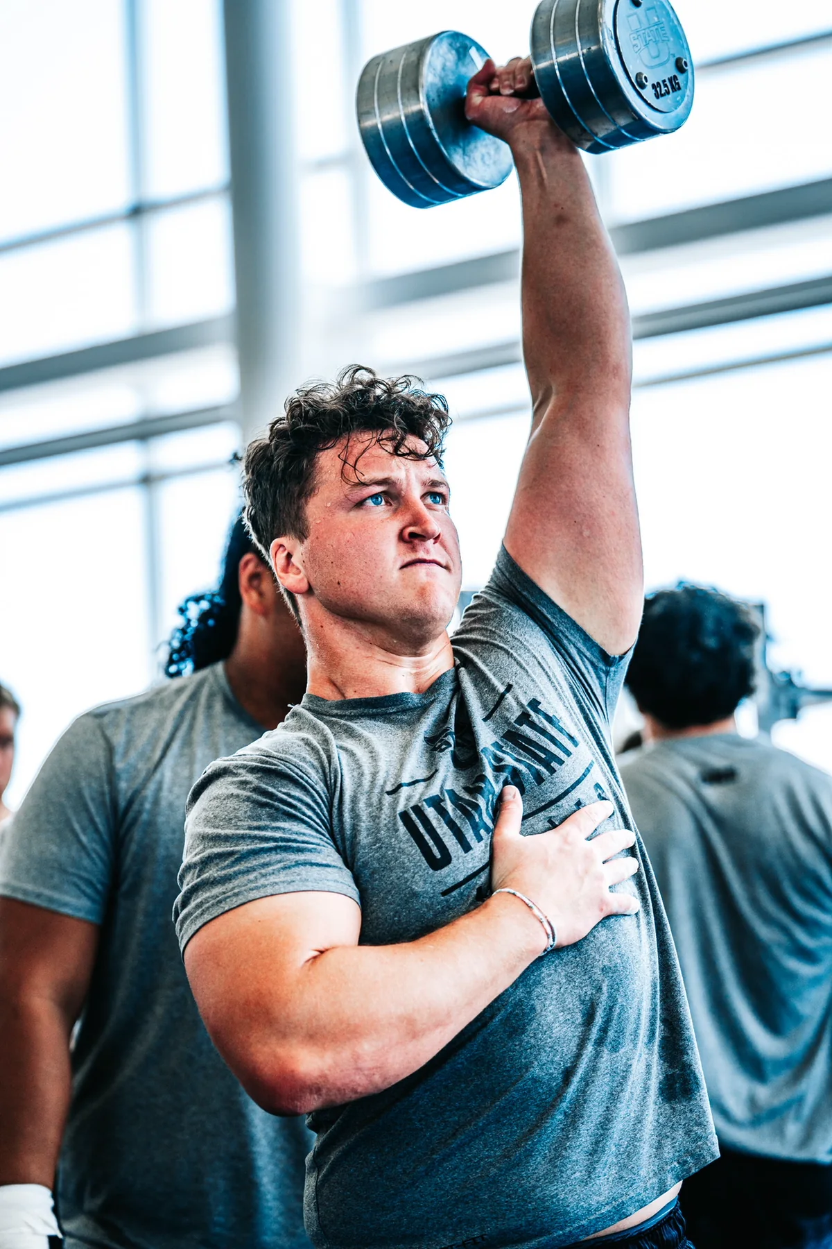 Kaden Jolley pressing a dumbbell overhead during a strength event